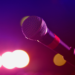 Ein Mikrofon vor einem violett beleuchteten Hintergrund.