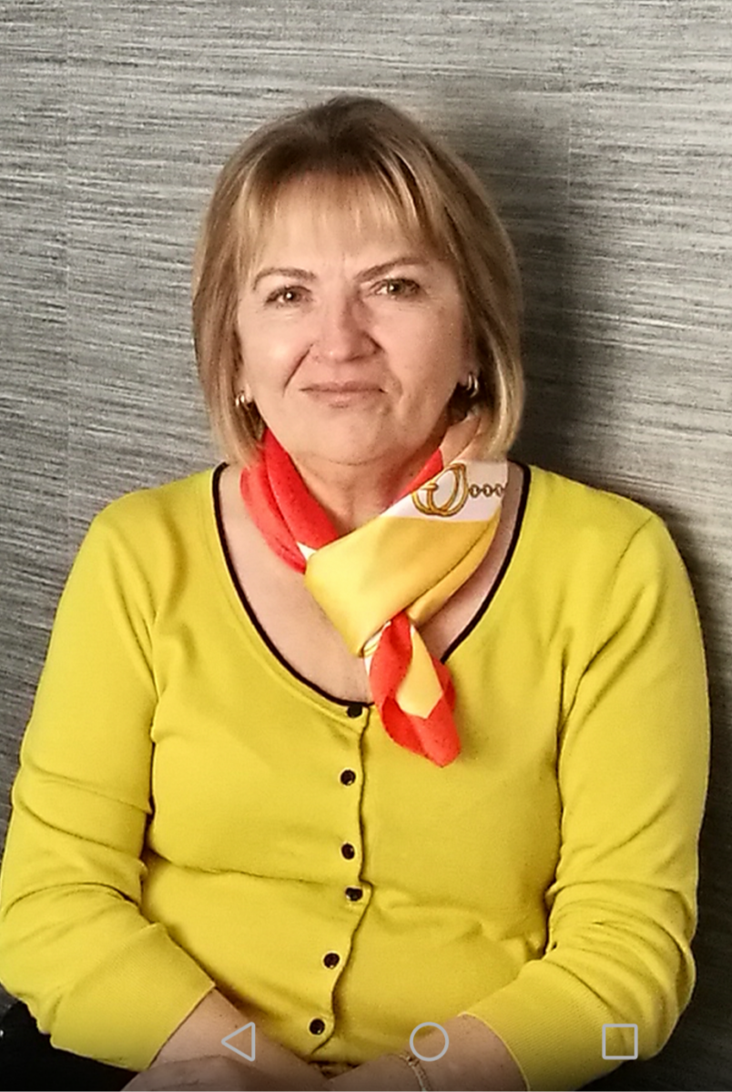 Eine Frau mit mittellangen Haaren und gelber Jacke.