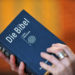 Zwei Hände halten eine blaue Luther-Bibel.