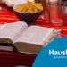Auf einem Tisch mit einer roten Tischdecke stehen Wassergläser und Snacks. Im Vordergrund liegt eine aufgeschlagene Bibel.