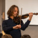 Ein Mann mit einer Violine spielt vor Publikum
