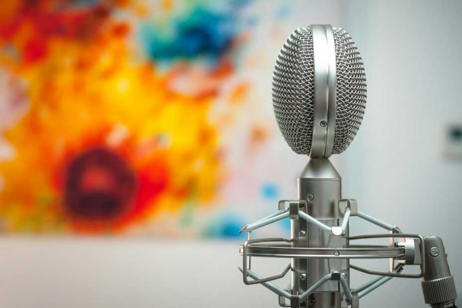 ein silbernes Studio-Mikrofon vor einem bunten verschwommenen Hintergrund
