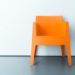 Ein oranger Stuhl vor einer weißen Wand