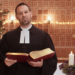 Pastor Marc Gommlich steht mit einer Bibel vor dem Weihnachtsbaum.