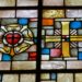 Ein Kirchenfenster zeigt die Lutherrose und ein Kreuz